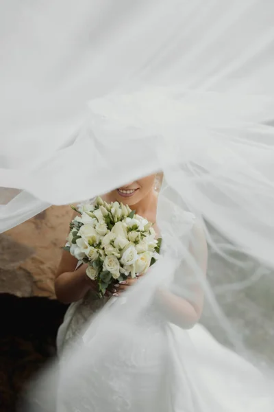 花嫁は大きな石の横にある山の中で高い岩の上に座っている ウェディングドレス ベールの下の花嫁 — ストック写真