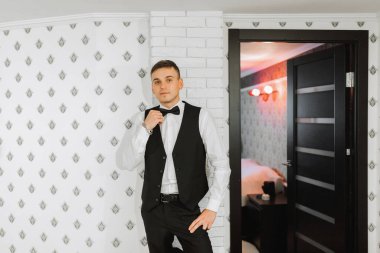 Şık damat elbiselerini giyer, düğün törenine hazırlanır. Büyük bir portre. Sabah ışığında harika bir iç mekan. Damadın sabahı.