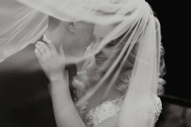 Damat ve gelin ormanda. Ormanda sonbahar düğünü. Mutlu düğün, duvağın altında sevgi dolu çift dokunuşları. Şık ve güzel. Uzun trenli prenses elbisesi. siyah beyaz fotoğraf