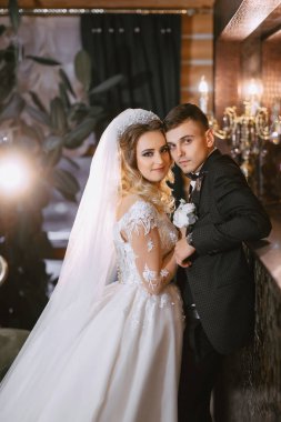Güzel bir saç stili olan güzel bir gelin ve güzel ahşap bir iç mekanda siyah takım elbiseli bir damat.