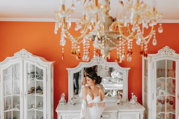 背の高い花嫁鏡の近くの部屋で裸の肩を持つオープンバスト 素晴らしい結婚式の髪型 レースローブ 肖像画 繊細なウェディングメイク — ストック写真