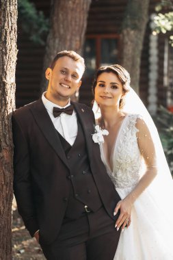 Genç damat ve düğün buketi ile ormanda bir düğün yürüyüşünde poz veren güzel gelin. Genç aile.