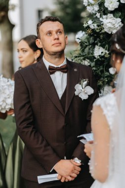 Düğün sonbahar seremonisinde güzel bir çift. Yuvarlak kemer beyaz çiçeklerle süslenmiş.