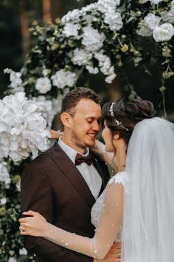 Düğün seremonisinden sonra mutlu gelin ve damat. yuvarlak tören kemeri. Gelinin uzun beyaz elbisesi
