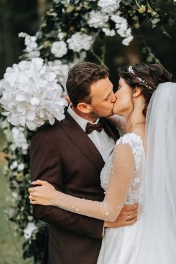 Düğün seremonisinden sonra mutlu gelin ve damat. yuvarlak tören kemeri. Gelinin uzun beyaz elbisesi