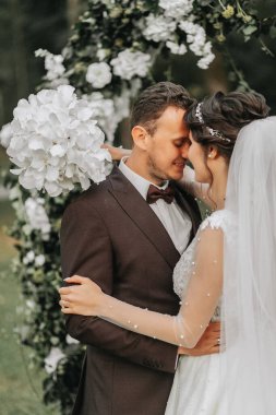 Düğün seremonisinden sonra mutlu gelin ve damat. yuvarlak tören kemeri. Gelinin uzun beyaz elbisesi