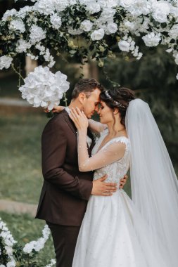 Düğün seremonisinden sonra mutlu gelin ve damat. yuvarlak tören kemeri. Gelinin uzun beyaz elbisesi
