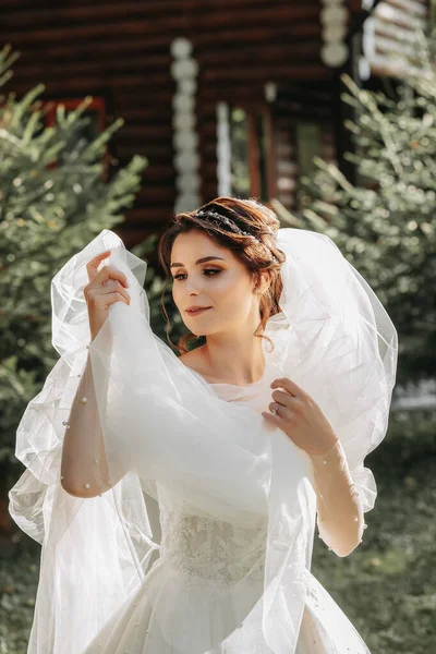 モダンな髪型とベールが庭 フロントビューを歩いて白いウェディングドレスで美しい花嫁の肖像画 結婚式のコンセプト — ストック写真