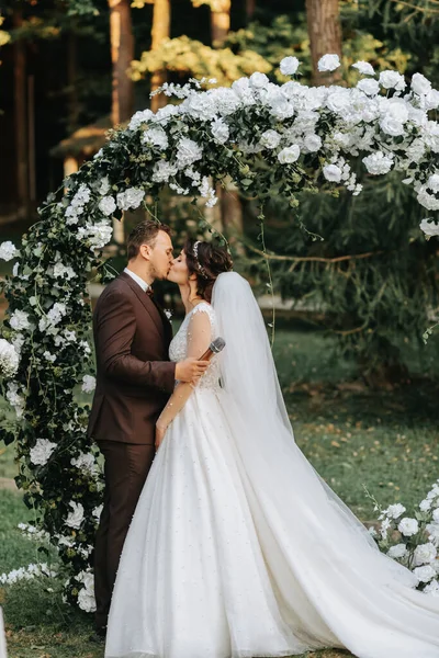 結婚式の秋の儀式で美しい結婚式のカップル 円形のアーチは白い花で飾られています — ストック写真