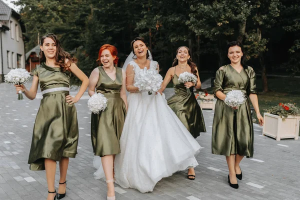 Beautiful bride and her friends- bridesmaids having fun after wedding ceremony. Happy girls at their best friend\'s wedding. Beautiful and elegant bride with bridesmaids walking on the stairs