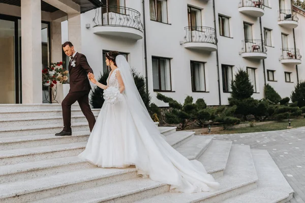 Жених Невеста Выходят Улицу Рядом Шикарным Отелем Длинный Поезд Платьев — стоковое фото