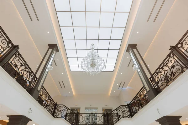 stock image Luxurious royal interior with a beautiful staircase and chandelier. Bright large hall with large windows