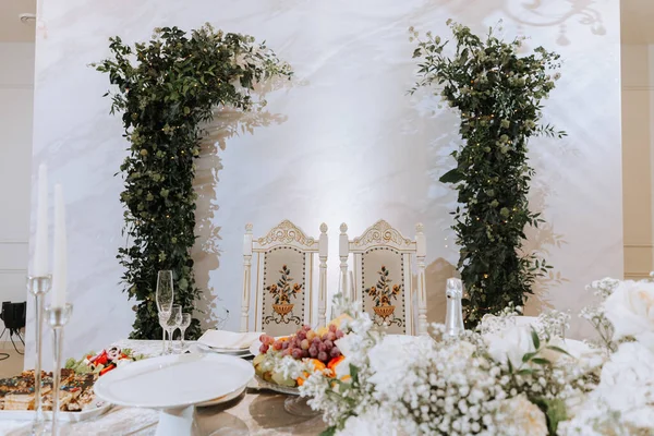 婚宴桌上服务 婚礼豪华装饰 新婚夫妇的婚纱 美丽的装饰与油腻的玫瑰 蜡烛和绿色 室内环境 — 图库照片