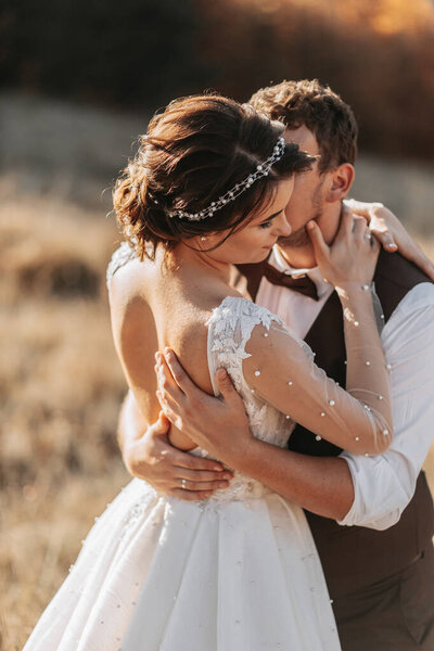 Beautiful wedding couple laughing and kissing against the background of stones. Dress with open shoulders. High quality photo