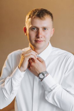 Damadın sabahı ve detaylar, beyaz gömlek, iyi ışık, genç adam, şık damat giyiniyor, düğün töreni için hazırlanıyor. Erkek ellerinin yakın çekimi,