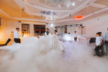 Gelin ve damadın düğünündeki ilk dans şık bir restoranda, harika bir ışık ve atmosferi olan. Yoğun duman