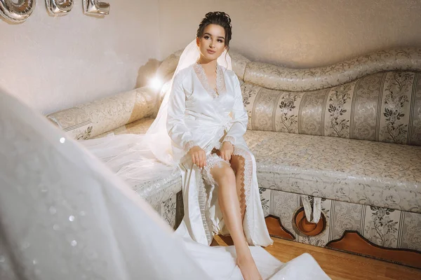 Brunette Bride Dressed Satin Robe Sits Sofa Next Her Dress — Stock Photo, Image