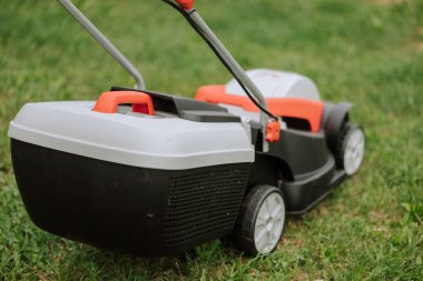 Modern bahçedeki yeşil çimlerde çim biçme makinesi. Çim biçme makinesi. Bahçe aletleri ile güvenlik ekipmanları