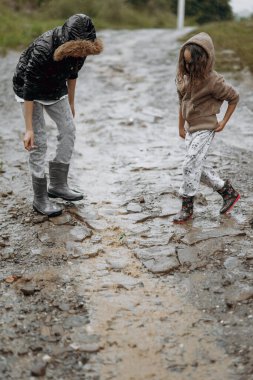 Avrupa görünümlü iki mutlu kız yazın yağmur altında su birikintilerinde oynuyorlar. Çocuklar yağmurda oynuyorlar. Doğada oynayan bir çocuk. Kız yağmuru seviyor..