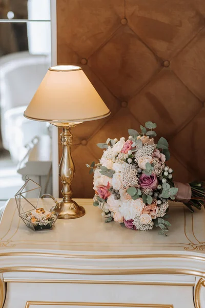 婚礼的细节从侧面拍了下来 背景是一盏夜灯 一束新娘花 一个装饰着鲜花的玻璃盒中的结婚戒指 — 图库照片