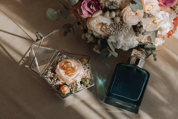 婚纱的细节图片来自上方灰色的纺织品背景 男人的香水 新娘的花束 结婚戒指在一个玻璃盒子里装饰着鲜花 — 图库照片