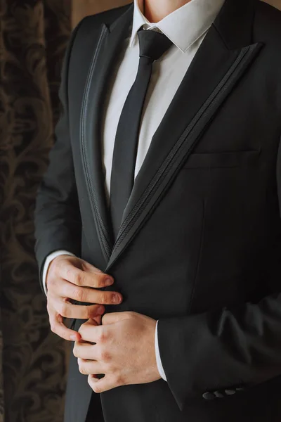 年轻人在他的房间里 在酒店房间的窗边 年轻的商人 把他的外套系在他的手上 拍了一张特写照片 新郎正在为婚礼做准备 — 图库照片