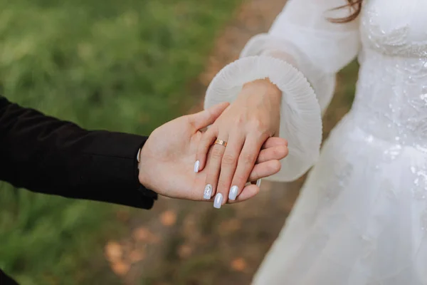 特写照片 新郎牵着新娘的手 金戒指戴在手上 照片中的柔情 模糊的背景 — 图库照片