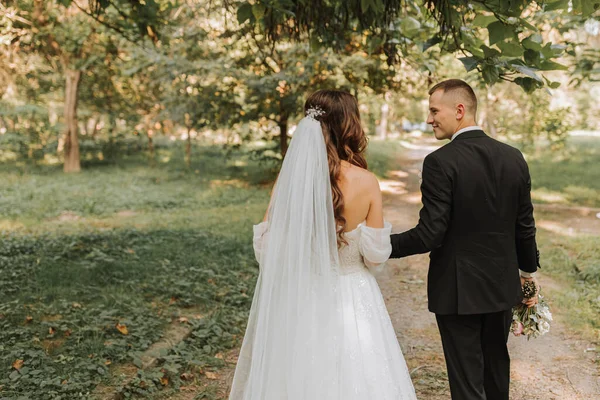 Menyasszony Vőlegény Fogják Egymás Kezét Sétálnak Kertben Nézik Egymást Fénykép — Stock Fotó