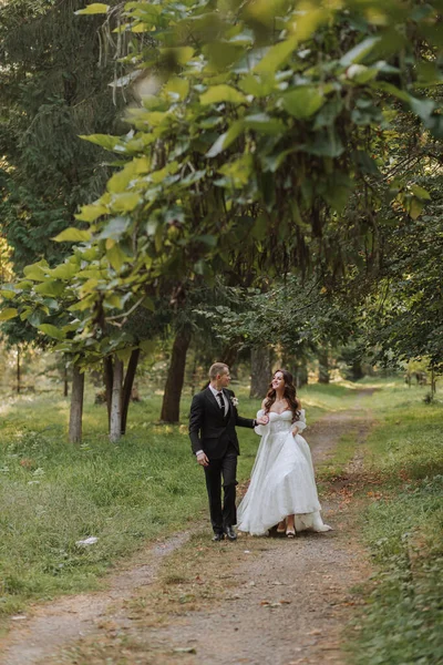 Νύφη Και Γαμπρός Κρατιούνται Χέρι Χέρι Περπατάνε Στον Κήπο Κοιταζόμενοι — Φωτογραφία Αρχείου