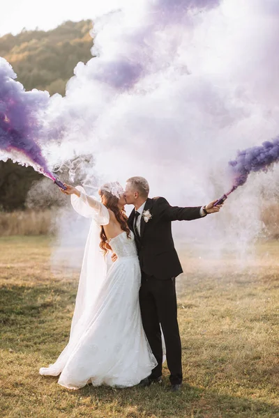 Gelin Damat Mor Ellerde Renkli Dumanlarla Oynuyorlar Sarılıp Öpüşüyorlar Düğünde — Stok fotoğraf