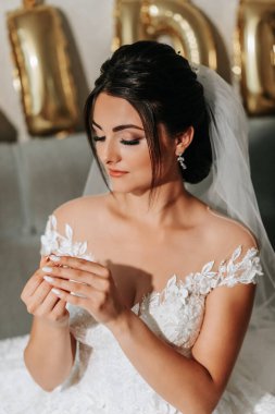 Gelinlik giymiş bir gelinin portresi, kız yüzüğünü parmaklarında tutuyor.