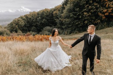 Romantik bir peri masalı çifti gün batımında eğrelti otu yapraklarının arkasında bir tarlada yürüyor. Gelin beyaz bir gelinlik, damat siyah klasik bir takım elbise ve beyaz bir gömlek giyiyor.