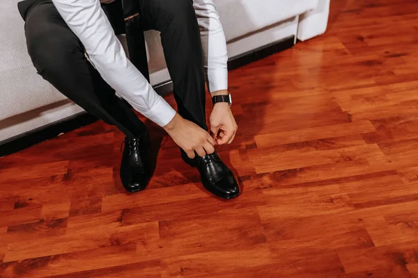 一个穿着白衬衫和黑色裤子的成熟男人正穿着鞋子坐在房间的沙发上 为婚礼做准备 特写照片 自由空间 — 图库照片