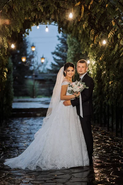 Das Brautpaar Abendpark Mit Einem Blumenstrauß Inmitten Der Abendlichter Grün — Stockfoto