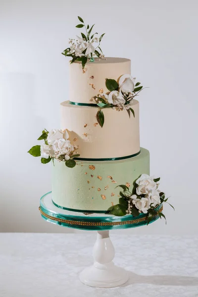 Wedding cake decorated with rose flowers in three tiers, isolated on a white background
