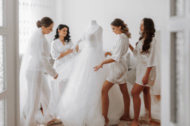 Gelinin kız arkadaşları gelinle birlikte gelinliğin yanına bakar. Gelin ve eğlenceli arkadaşları uygun elbiselerle bir bekarlığa veda partisi düzenliyorlar..