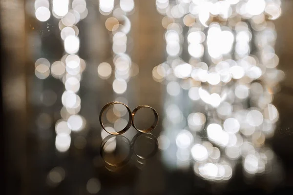 背景にゴージャスなボケが付いた鏡面の結婚指輪のマクロショット — ストック写真