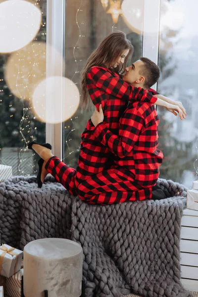 Młoda Piękna Para Małżeńska Identycznej Czerwonej Piżamie Parapecie Przytulająca Się — Zdjęcie stockowe