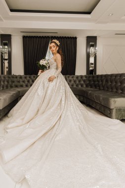 Pahalı bir elbisesi ve uzun bir treni olan genç bir prenses sırtı kameraya dönük duruyor. Şık moda.