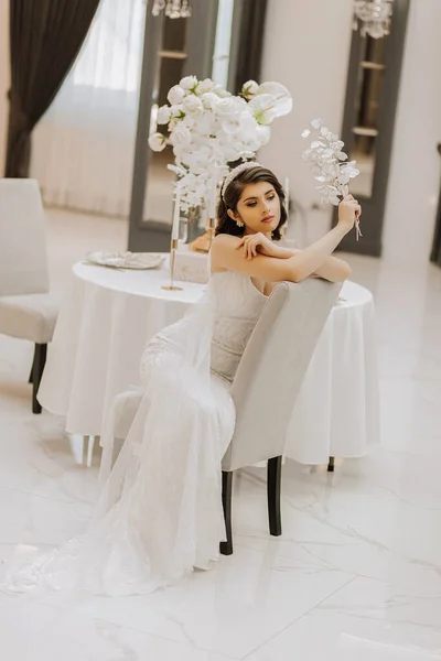 一个穿着婚纱的漂亮姑娘的画像 新娘穿着华丽的衣服 坐在椅子上 垂直照片 — 图库照片