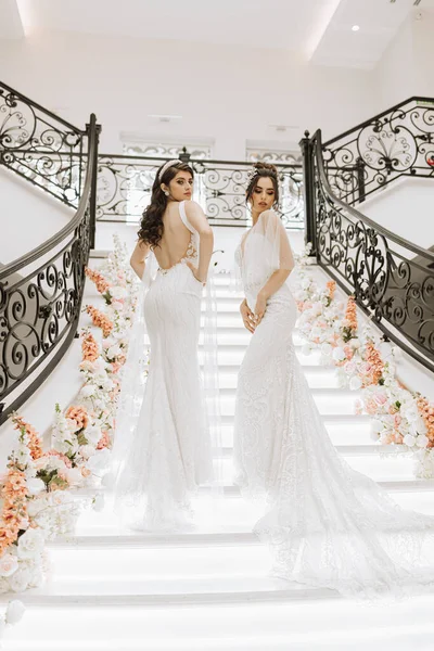 Két Gyönyörű Lány Menyasszonyi Ruhában Pózol Egy Virágokkal Díszített Étterem — Stock Fotó