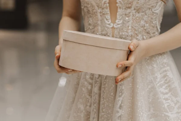 Portrait of a girl in a wedding dress with a round box in her hands with free space for a signature. horizontal photo.
