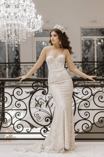 一个穿着婚纱的女孩在黑金属栏杆附近的摄影棚照片 一个大吊灯 白色豪华室内装饰风格 — 图库照片