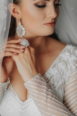 Ayrıntılar. Düğün aksesuarları. Esmer bir gelin, kristal bir evlilik yüzüğüyle güzel bir şekilde el ele tutuşur. Kesilmiş fotoğraf. Güzel eller. Açık büst. Kristal mücevherler