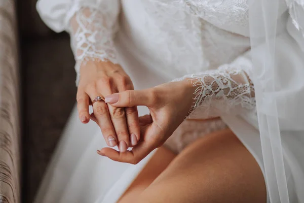 Details Wedding accessories. The bride holds a gold wedding ring with a diamond in her hands, cropped photo. Beautiful hands. Open legs
