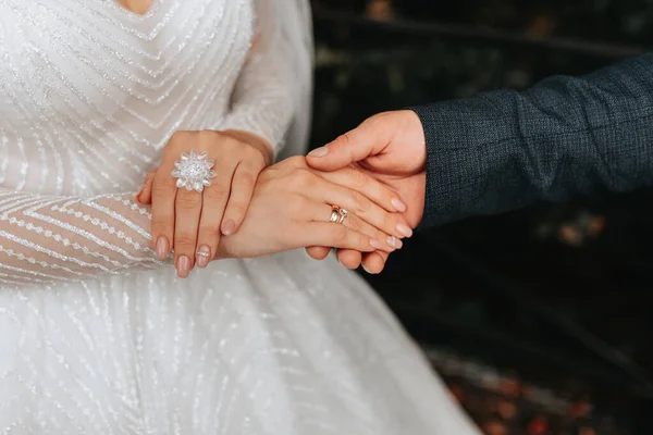 婚礼配件的细节 新娘手里拿着一朵白玫瑰 一只手上拿着水晶的漂亮的结婚戒指 剪过的照片美丽的手 — 图库照片