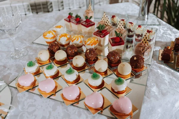 Festive dessert table with sweets. Wedding candy bar, various cakes, chocolates on stands.