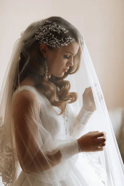 一个穿着婚纱袖子婚纱的金发新娘的画像 站在她的房间里 — 图库照片