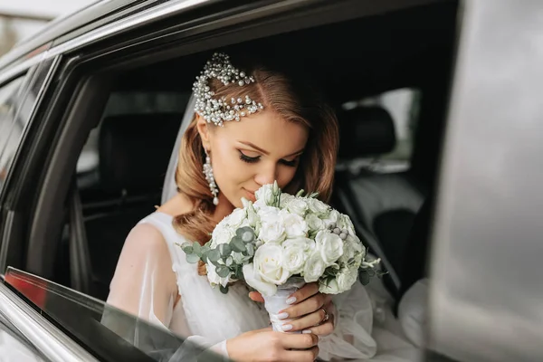 close-up portrait of a rather shy bride in a car window looking at her bouquet of flowers