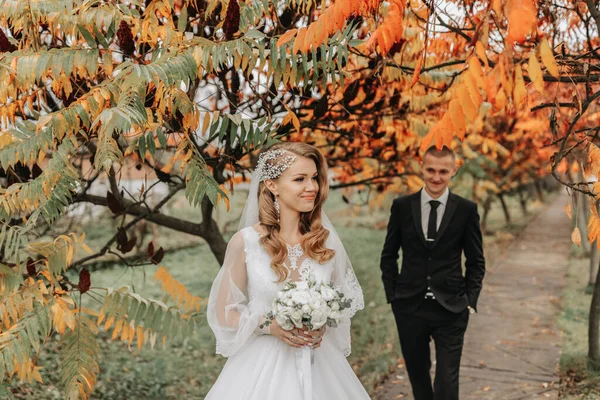 공원에서 사랑에 커플의 초상화 소매와 그녀의 꽃다발과 결혼식 드레스에 금발의 — 스톡 사진